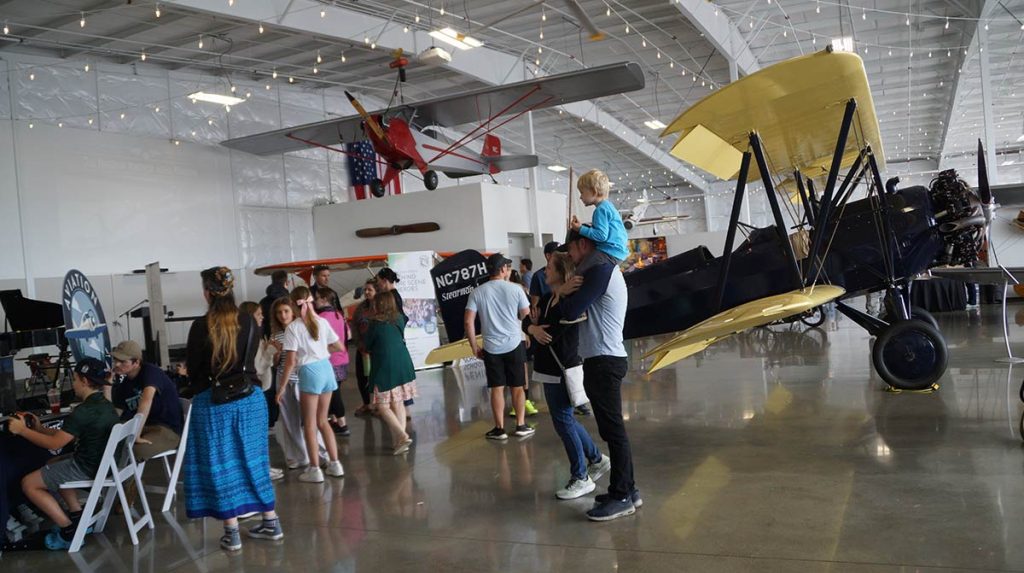 Visitors to the museum on Airport Day mill around with a bi-plane in the background.